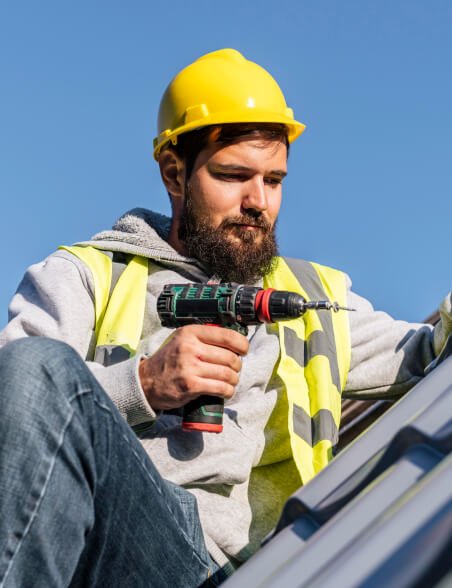 Roofing specialist in yellow helmet using power drill during residential roof installation in Cincinnati